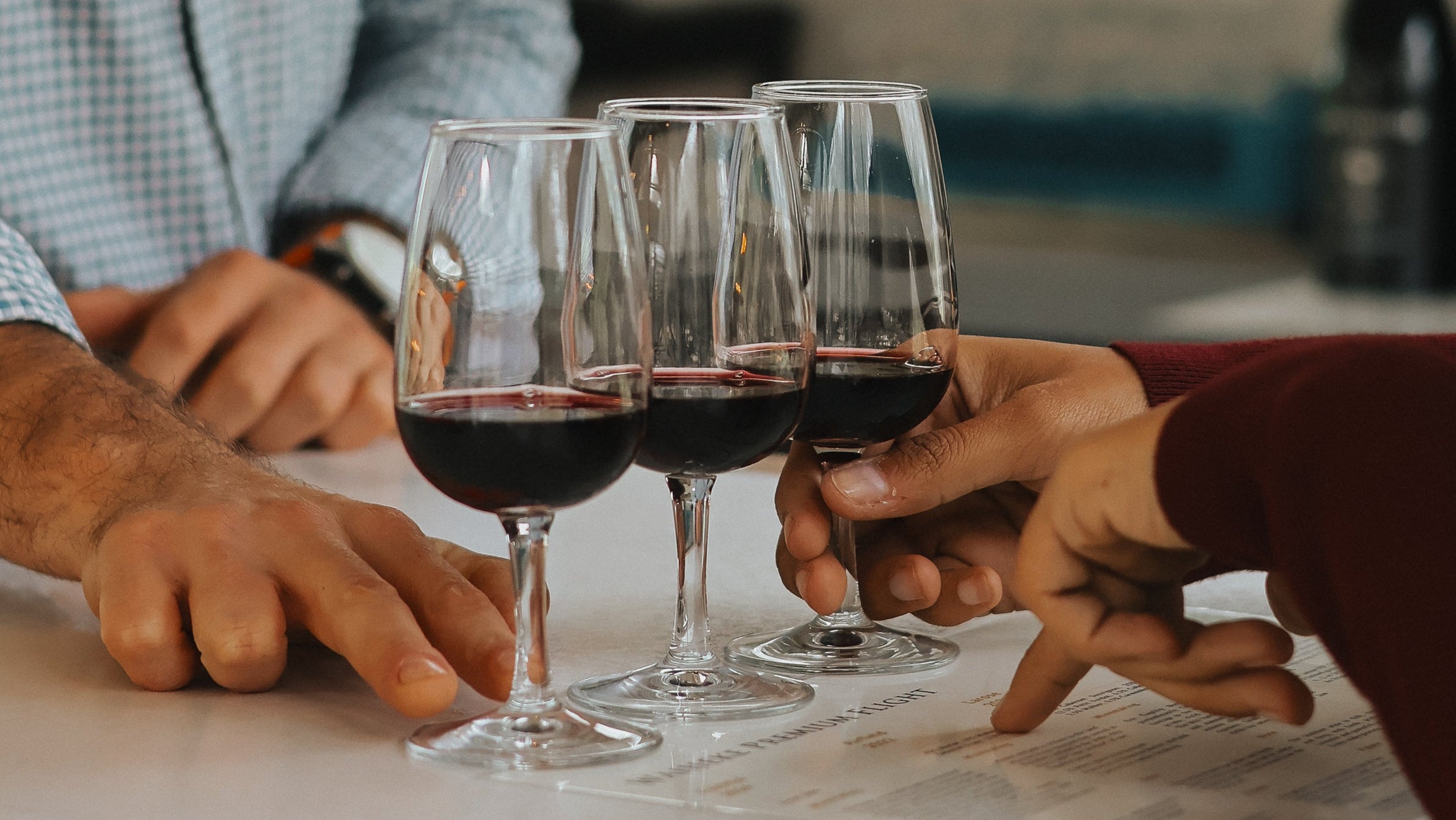 Two people tasting wine in a casual setting with bottles and glasses on a table.